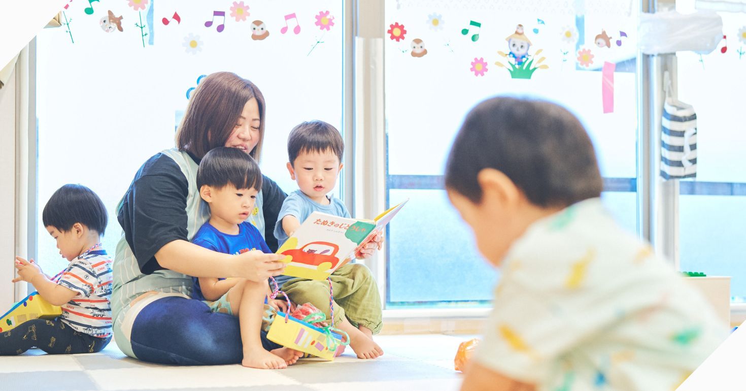 保育園で絵本を楽しむ子どもたちと保育士